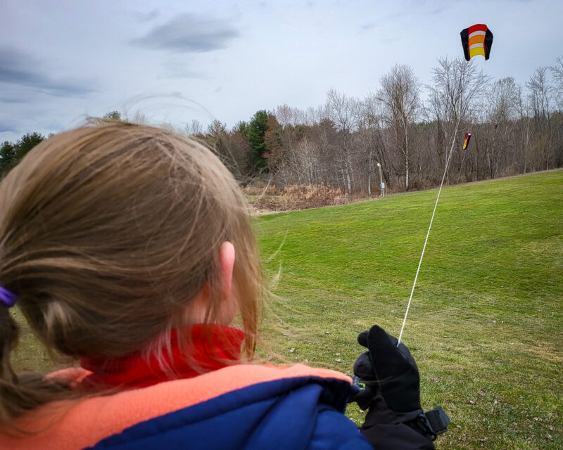child flying kite on overcast day