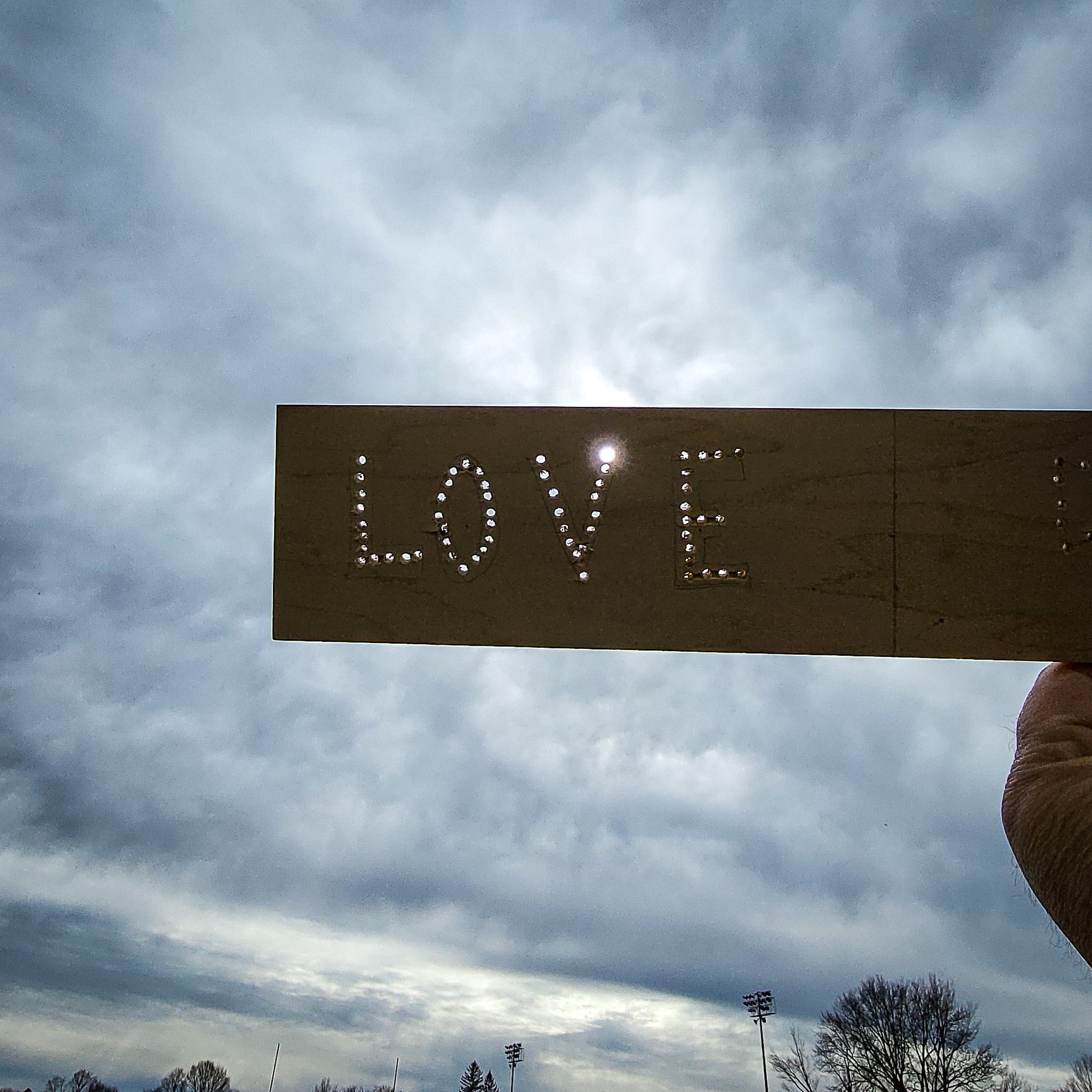 the word love punched into a piece of wood, illuminated by the just after eclipse sun