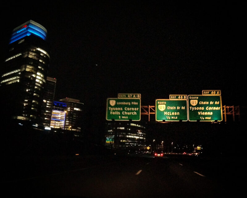 highway signs next to colorful lit building at tysons corner vienna virginia