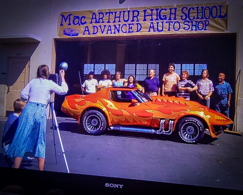 spicy chevrolet corvette in front of high school group photo