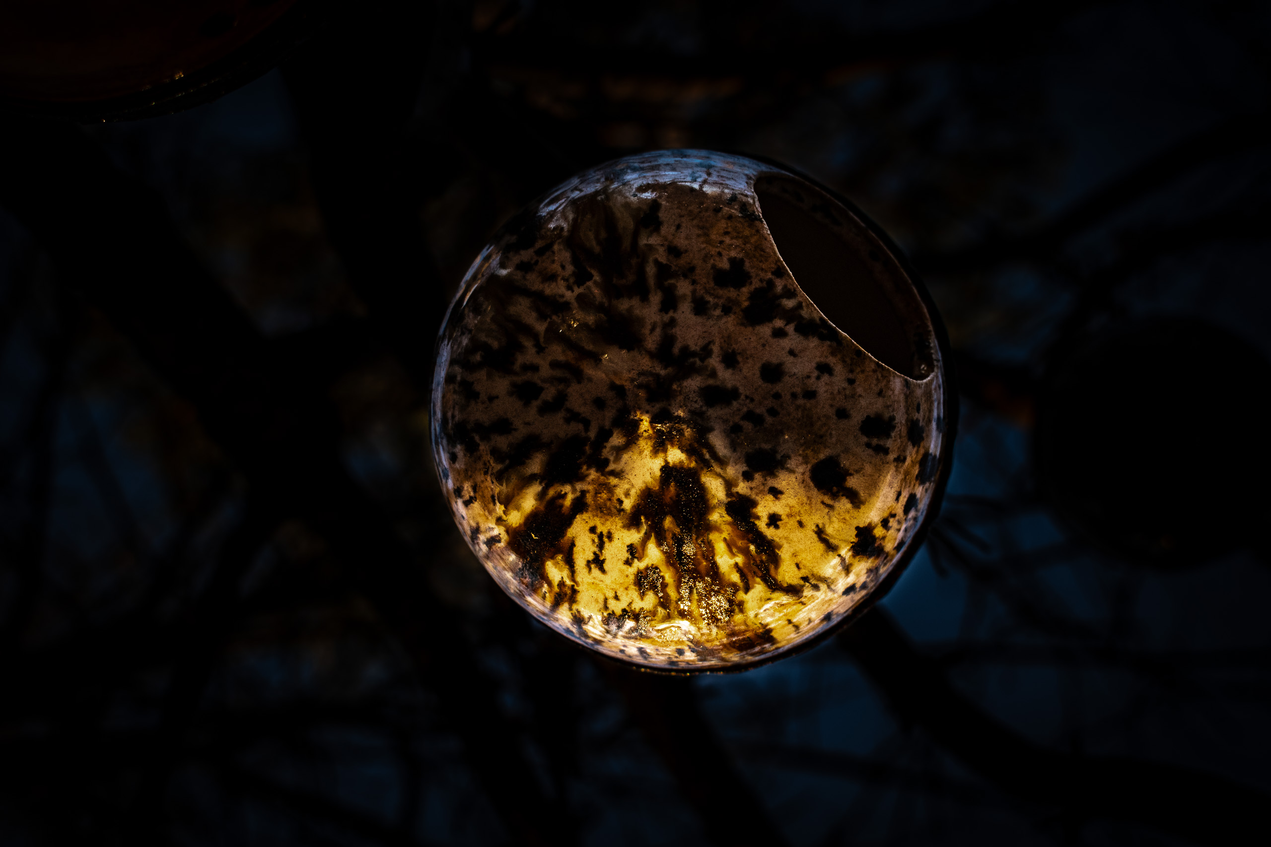 pottery bird house, globe shaped, shot from below with dramatic coloring on a dark background